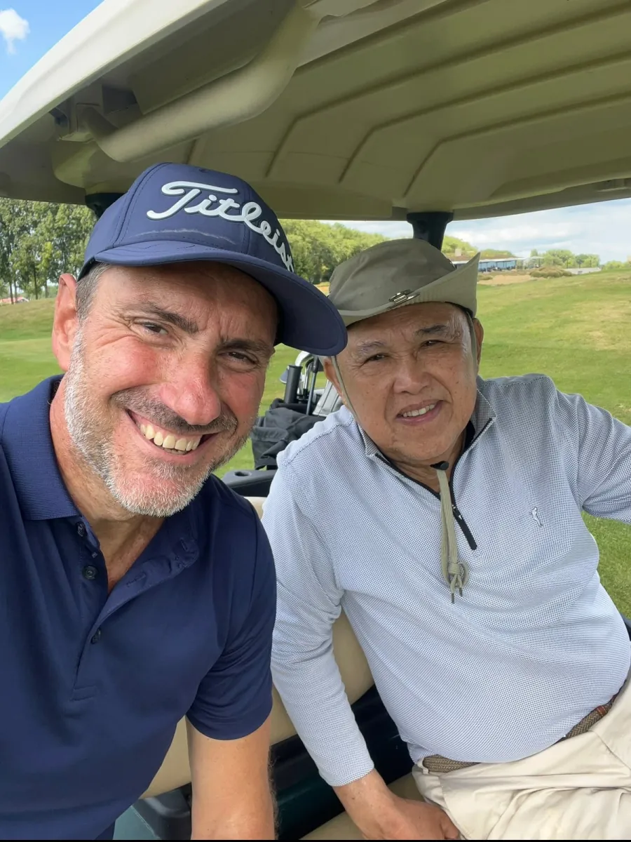 Pedro Nogueira with a fellow golfer in a cart on the course
